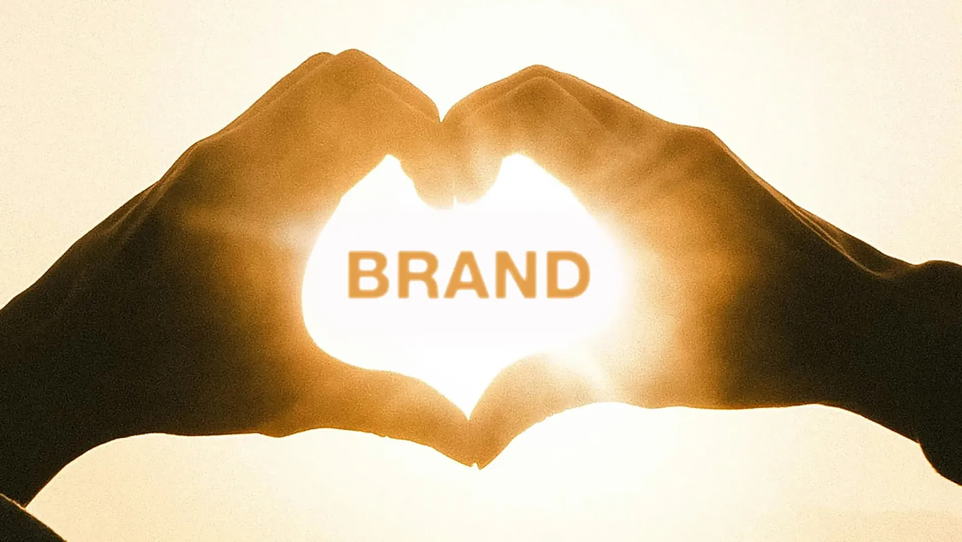 Sun burst through hands making a heart shape with the word ‘brand’ emblazoned across it
